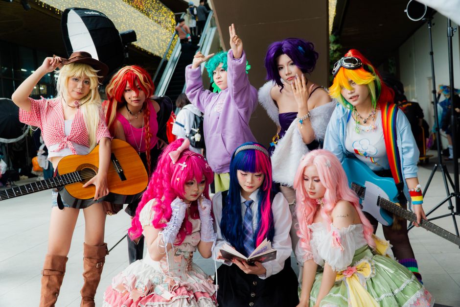 Cosplay enthusiast poses in colorful attire with lavender hair outdoors in Vietnam.