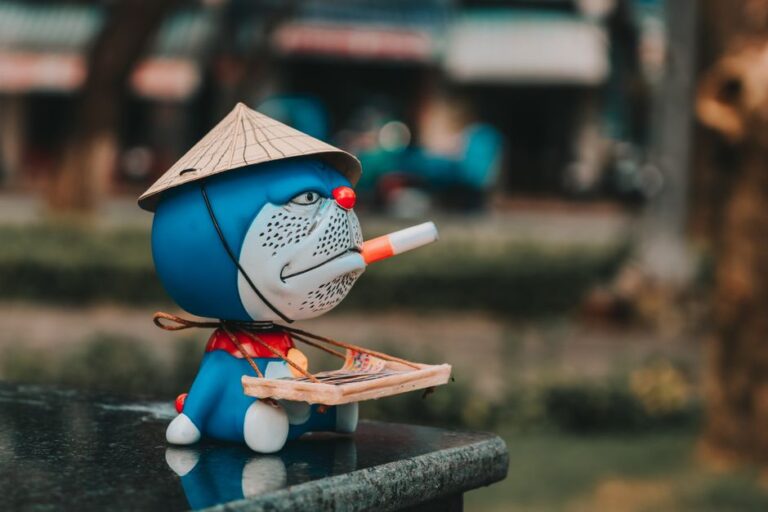 Colorful figurine of a character wearing a Vietnamese hat and holding a cigarette outdoors.